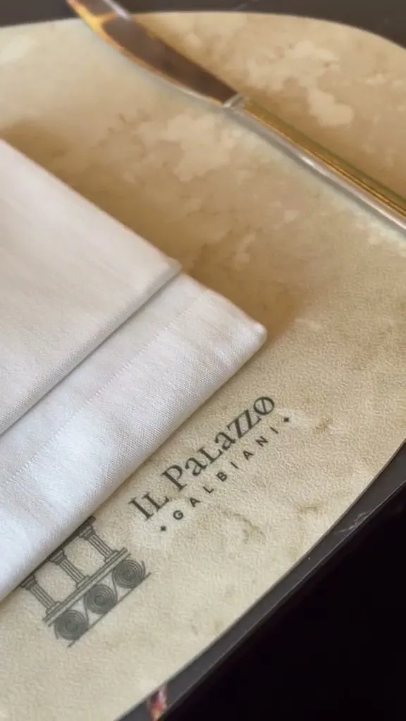 The Il Palazzo Galbiani mark embossed on the placemat, beside a folded napkin