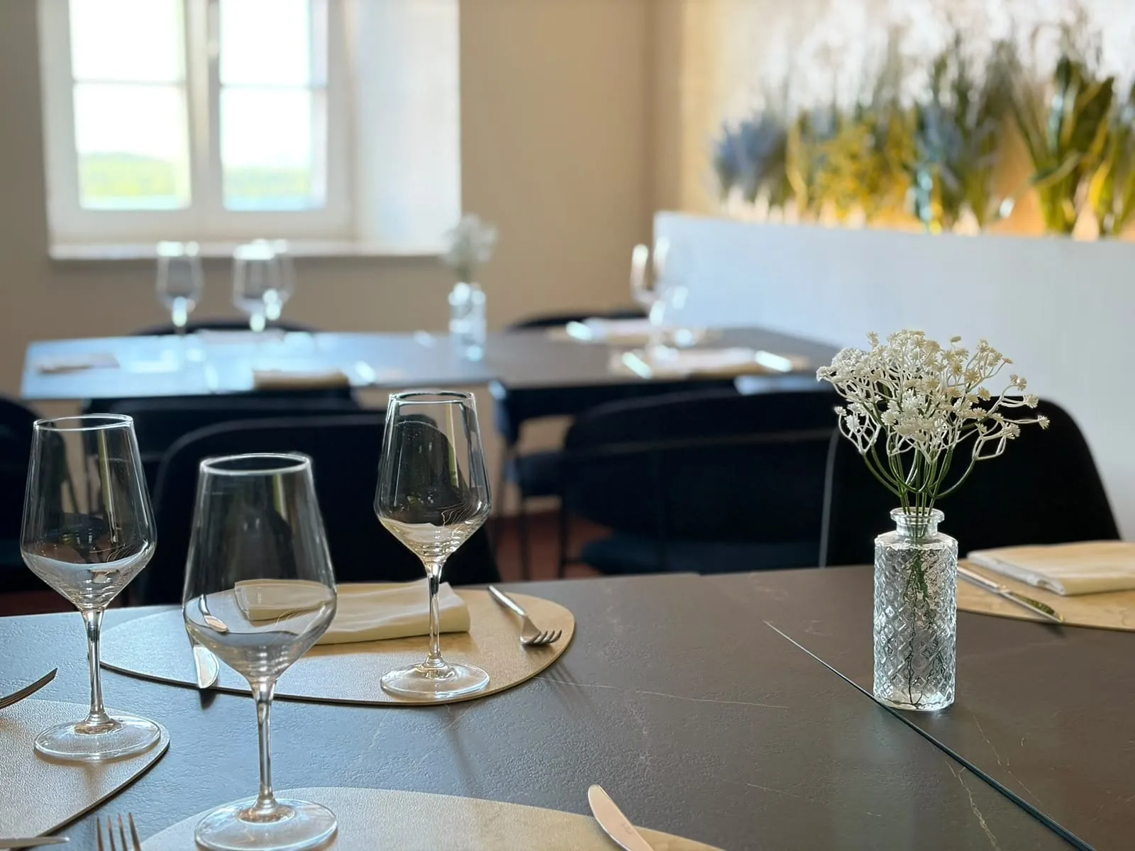 Pripremljeni stolovi u unutarnjem dijelu restorana, čaše i cvijeće na stolu