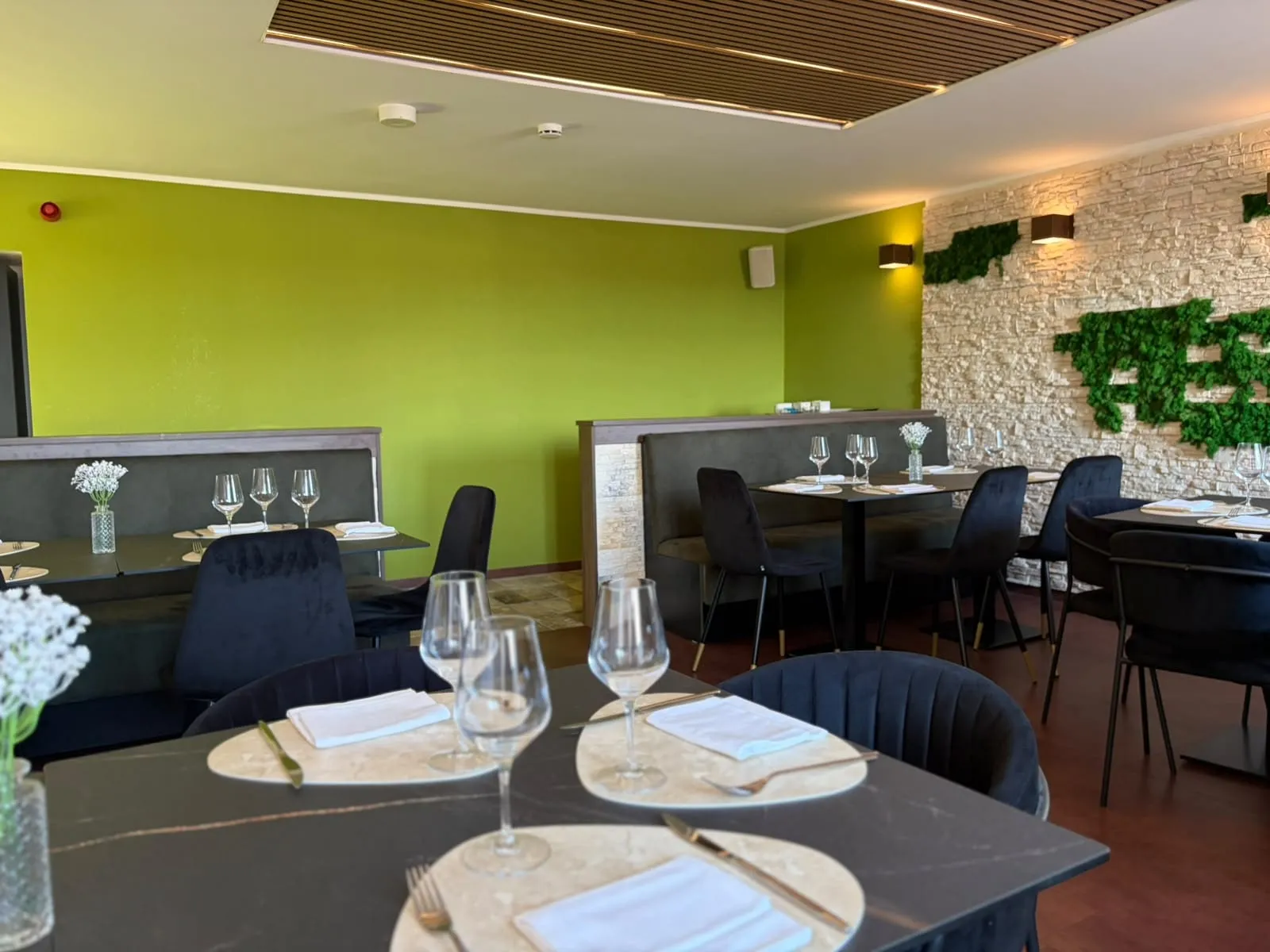 Unutarnji dio restorana sa stolovima i kamenim zidom